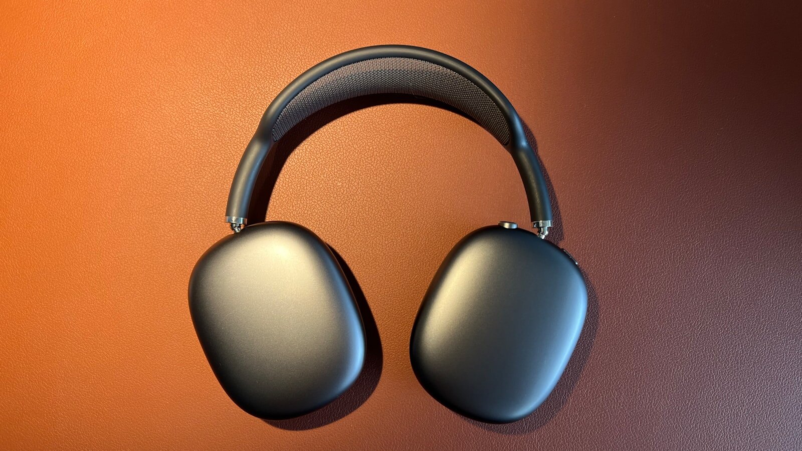 Photo of space gray Apple AirPods Max on a brown surface