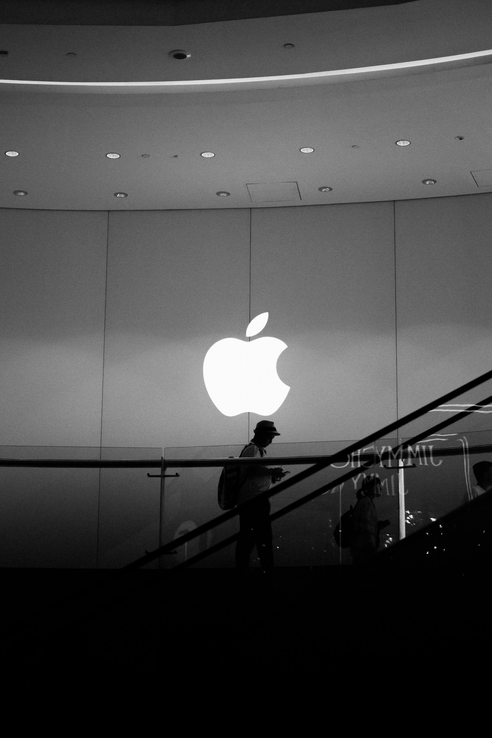 Black and white photograph of an Apple Store, with the Apple logo above a staircase