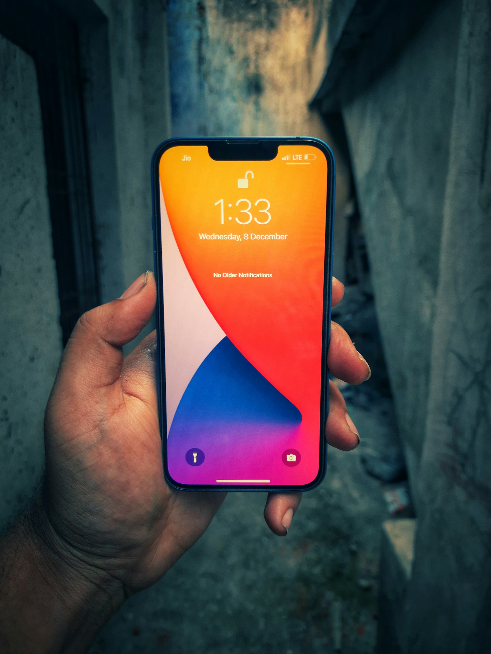 片手で持たれたiPhone、ロック画面が表示されている