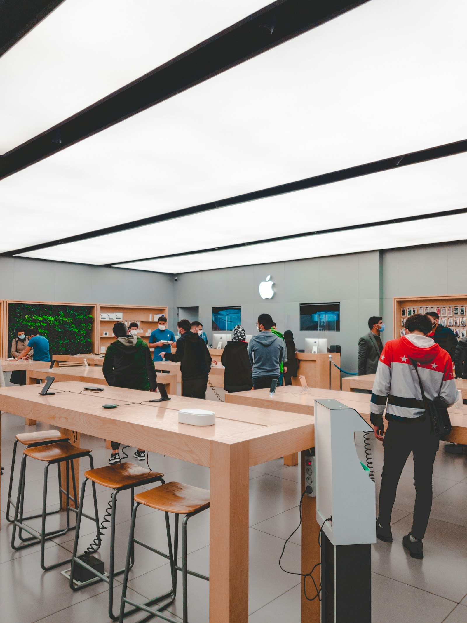 Apple Storeの店内で展示テーブルを見て回る来店客。iPhone 18の供給網をめぐる報道を説明するイメージ写真。
