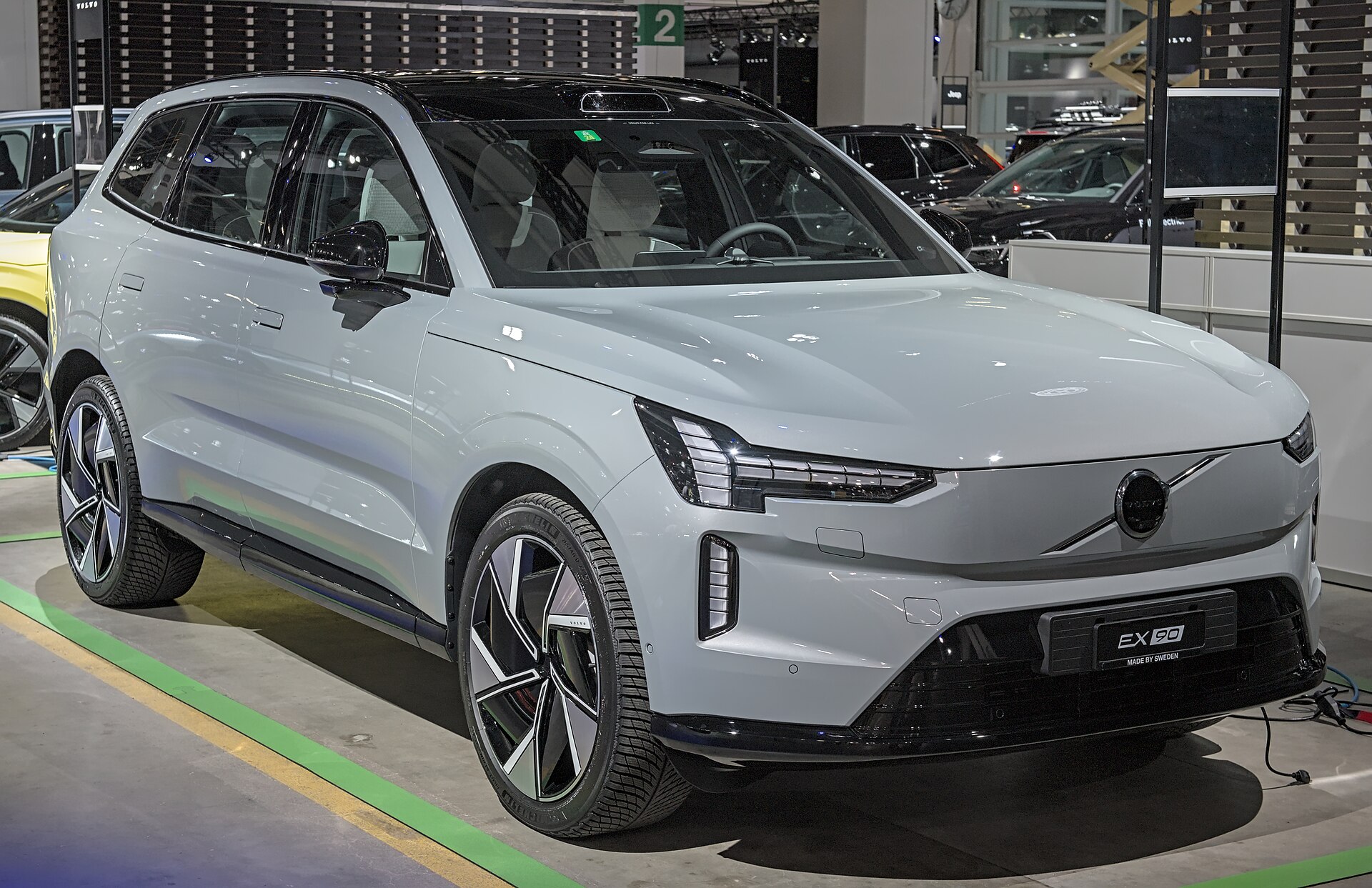 A white Volvo EX90 displayed in a showroom; the photograph does not show the CarPlay interface or audio system.