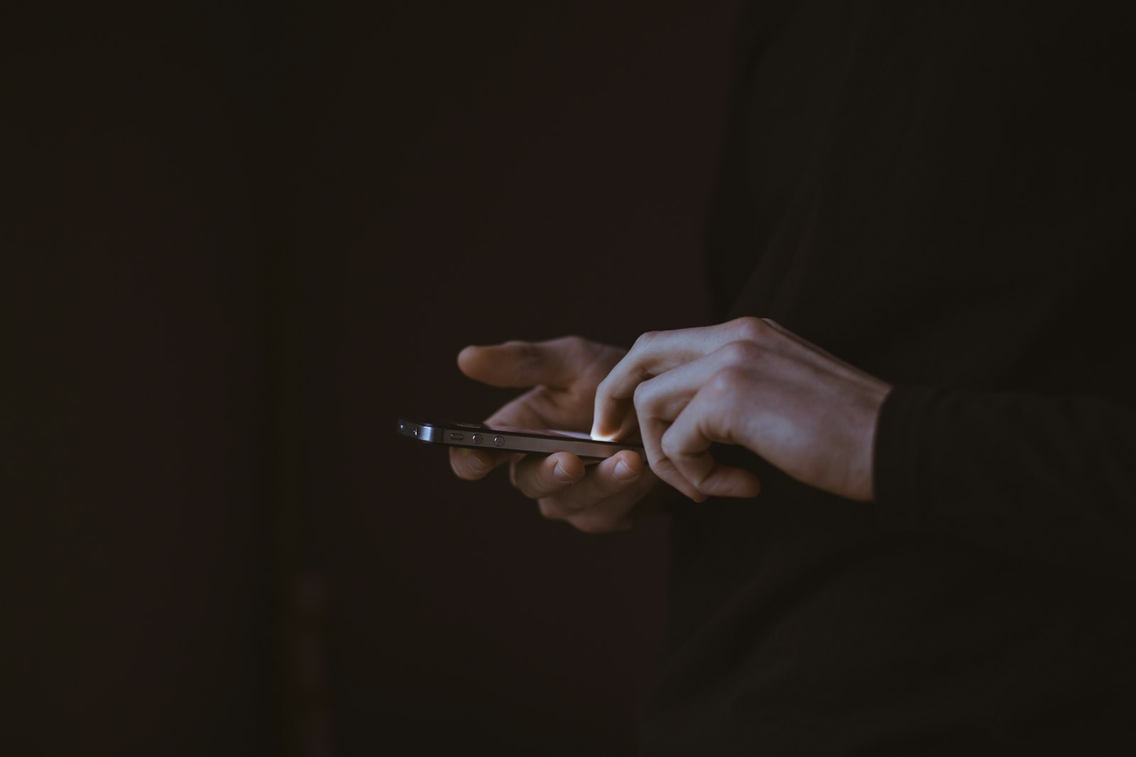 Unas manos sostienen un smartphone con poca luz